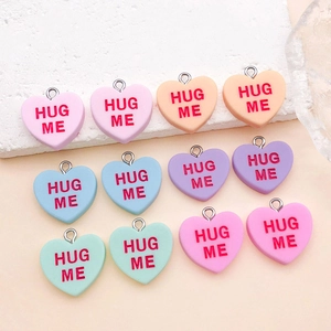 Close-up of assorted colorful resin heart charms with Hug Me text for DIY jewelry making