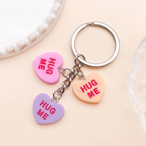 Detail of pink, orange and purple resin heart charms with Hug Me text on a keychain