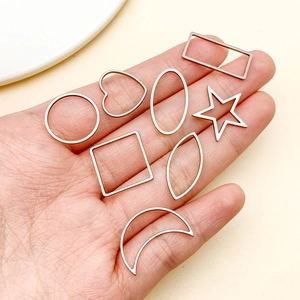 Detalle de marcos metálicos geométricos oro rosa para joyería DIY sobre una mano