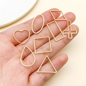 Close-up of golden geometric frames for DIY jewelry charms in assorted shapes held by hand
