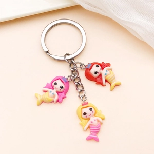 Detail of keychain with three cute cartoon mermaid charms in pink, red and yellow hair