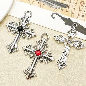 Detailed view of gothic cross pendants with red and black gems and hollow patterns