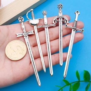 Détail d'un lot de 5 pendentifs épée en argent antique avec pièce pour comparer la taille