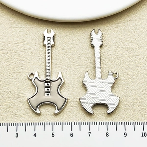 Détail macro du pendentif guitare argenté montrant l'avant, l'arrière et la règle de mesure