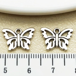 Detailed macro view showing a 15mm antique silver butterfly charm with ruler measurement