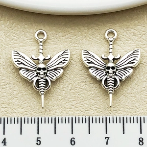 Macro view of gothic silver moth pendants with skull and dagger detail for DIY jewelry