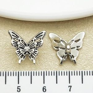 Detailed macro view of antique silver hollow butterfly charms for DIY jewelry making