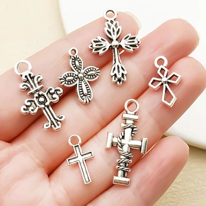 Détail de six pendentifs croix en argent antique tenus à la main pour l'échelle réelle