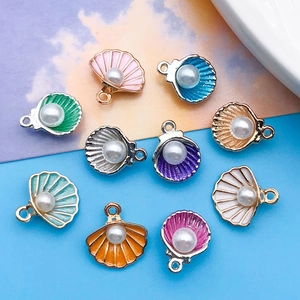 Vue détaillée de pendentifs coquillages colorés en alliage avec perles et finition émail