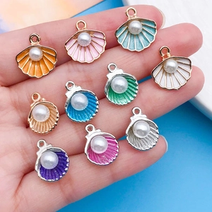 Gros plan de pendentifs coquillages en émail coloré avec perles sur une main humaine