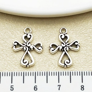 Détails de pendentifs croix en argent vintage avec motifs de cœur près d'une règle