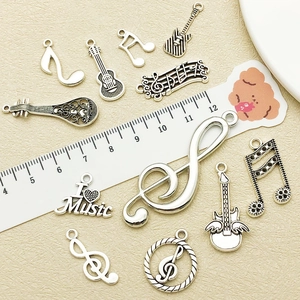 Detailed view of silver antique music charms including guitar and notes with a ruler scale
