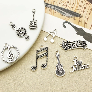 Detailed close-up of antique silver music charms with guitars and musical notes