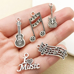Close-up of antique silver music charms including guitar and I Love Music heart designs