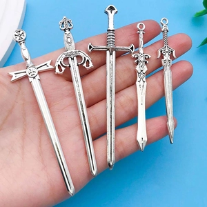 Detail view of five vintage silver zinc alloy sword pendants held by hand for size reference