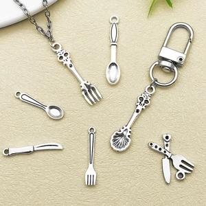 Detailaufnahme antiker Miniatur-Besteckanhänger aus Silber mit geprägten Blumenmustern