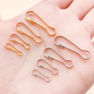 Macro view of gold and silver gourd-shaped safety pins in four sizes on a palm