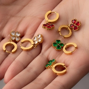 Detailed macro view of three four-leaf clover earrings with red, white, and green zircons