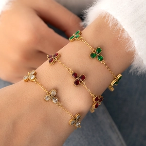 Dettaglio di tre braccialetti a quadrifoglio con pietre di zircone verdi, rosse e bianche