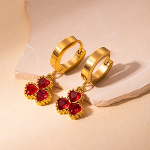 Detailed close-up of 18K gold earrings with red heart-shaped stones on stone decor