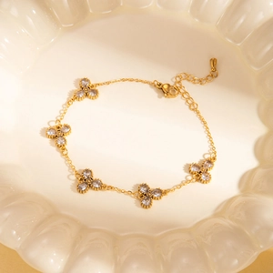 Dettaglio del bracciale a quadrifoglio dorato con pietre in zircone in ciotola di ceramica