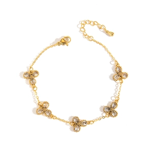 Detailaufnahme von Gold-Titan-Armband mit Kleeblatt-Motiven und klaren Zirkonia