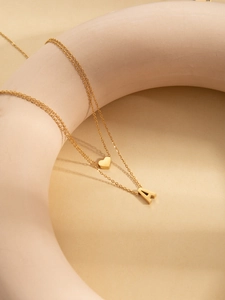 Detail of double-layer gold titanium steel necklace with heart and A letter pendants