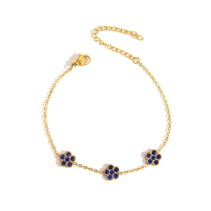 Detail eines Gold-Titanarmbands mit blauen Strass-Blumenanhängern und verstellbarer Kette