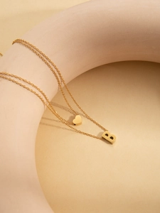 Close-up of double layer gold necklace featuring a heart charm and uppercase B pendant