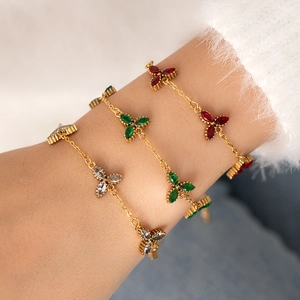 Dettaglio macro di braccialetti a quadrifoglio dorati con pietre di zircone multicolore