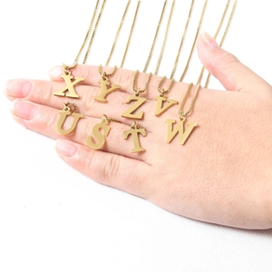 Detail of gold letter pendants on dainty square link chains held in hand