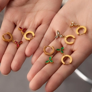 Detailed view of gold hoop earrings with zircon clover charms in red white and green