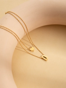 Close-up of gold titanium steel layered necklaces with heart and D letter pendants