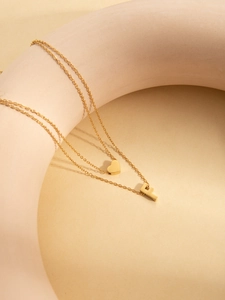 Detail of gold titanium steel double layer necklace with heart and letter F pendants