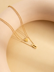 Detail of gold double-layer necklace featuring heart pendant and bold letter G charm