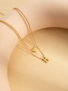 Close-up of double-layered gold-plated necklace with heart and letter H pendants