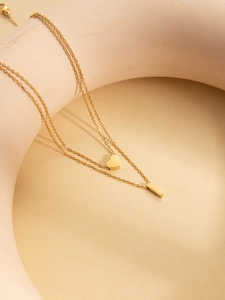 Detailed macro shot of a gold double-layer necklace featuring heart and bar pendants