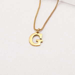 Macro shot of polished gold-plated letter G pendant on a stainless steel box chain