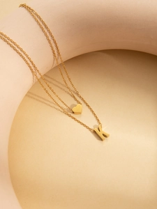 Detailed macro view of a layered gold-plated necklace with a heart and K-letter pendant