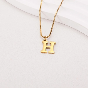 Detailed close-up of a gold H-letter pendant on a box chain with a polished metallic finish