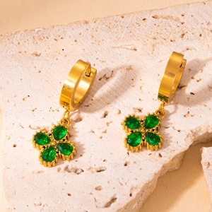Detailed close-up of 18K gold clover earrings with green pear-shaped zircons
