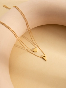 Close-up of double-layer gold necklace featuring a heart charm and a capital letter P pendant
