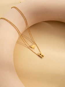 Detailed close-up of double-layer gold plated necklace with heart and letter R pendants