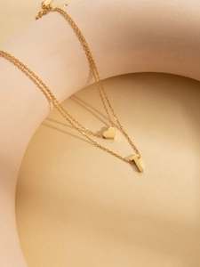 Detail of double-layer gold plated necklace with small heart and letter T pendants