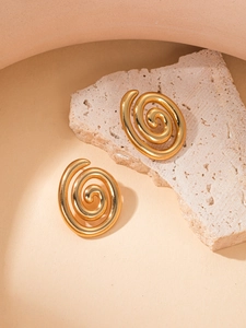 Primer plano de pendientes de espiral dorados sobre soporte de piedra natural