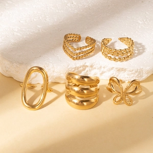 Macro detail of five-piece gold ring set featuring irregular lines and butterfly motifs