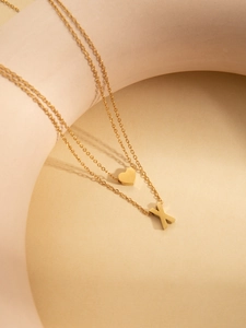 Close-up of gold double-layer necklace featuring heart and letter X pendants on display
