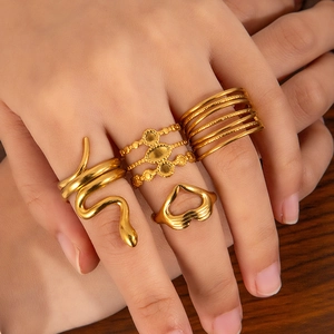 Detail of four gold stainless steel rings with snake, beaded, and heart designs on hand