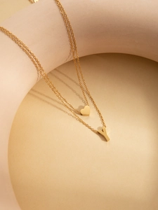 Detail of double-layer gold titanium necklace with heart and letter Y pendant charm