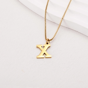 Macro view of golden letter X pendant with elegant box chain on textured background